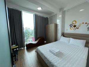 a bedroom with a white bed and a large window at Hotel Hồng Cẩm in Trung An