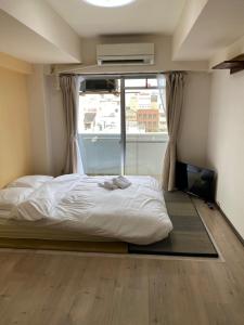 een slaapkamer met een bed en een groot raam bij La Foret Fujimi in Hiroshima