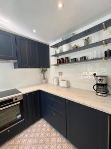 Una cocina con gabinetes azules y una encimera. en The Raven's Loft by Harry Potter, en Garston
