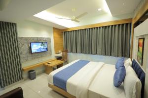 1 dormitorio con 1 cama y TV. en HOTEL RK FORTUNE en Ahmedabad