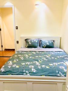 uma cama com um edredão azul com flores em Osaka Đà Lạt Apartment em Xuan An