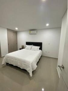 Un dormitorio blanco con una gran cama blanca. en Apartamento en exclusivo lugar de Neiva, en Neiva