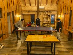 tres hombres jugando ping pong en una habitación con una mesa en Hostal Entre Los Lagos en Villarrica