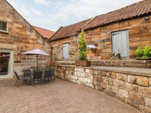 a patio with chairs and an umbrella next to a brick building at Mulgrave Cottage in Staithes