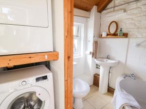 a bathroom with a washing machine and a sink at Llety'r Wennol in Llanycrwys +25 photos