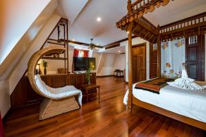 a bedroom with a canopy bed and a chair at Royal Crown Hotel & Spa in Siem Reap