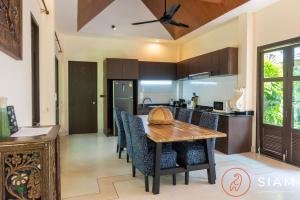 Il comprend une cuisine et une salle à manger avec une table et des chaises en bois. dans l'établissement Villa BangKao 3Br Pool & Walk to Beach, à Nathon Bay