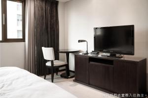 Habitación de hotel con TV, mesa y silla en Talmud Hotel Kaohsiung LoveRiver en Kaohsiung