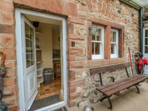 a brick building with a bench next to a door at Blacksmith Cottage in Appleby