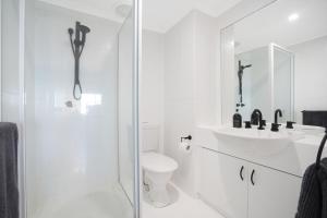 Baño blanco con aseo y lavamanos en Welcome Homestay Gurambai, en Darwin