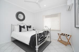 a white bedroom with a bed and a mirror at Welcome Homestay Gurambai in Darwin