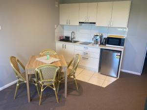 cocina con mesa, sillas y microondas en Central Oasis en Coffs Harbour