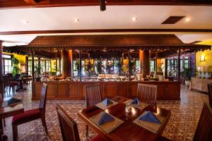 a restaurant with a bar with wooden tables and chairs at Royal Crown Hotel & Spa in Siem Reap