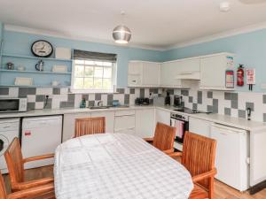 a kitchen with white cabinets and a table and chairs at Bella's Cottage in Great Driffield