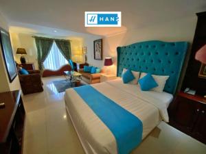a bedroom with a blue bed and a living room at HANZ Vuon Saigon Hotel & Spa in Ho Chi Minh City