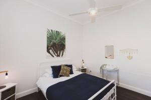 a bedroom with a white bed with blue and gold pillows at Halcyon Days the perfect getaway, pet friendly! in Cessnock