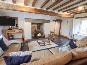 a living room with a couch and a fireplace at Satterthwaite Farmhouse - Sleep 8 in Grizedale