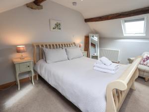 1 dormitorio con 1 cama blanca grande y toallas. en Satterthwaite Farmhouse - Sleep 8 en Grizedale