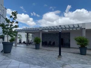 une pergola avec des chaises et des tables sur une terrasse dans l'établissement Nuevo y amplio departamento con alberca y seguridad en el centro de Guadalajara, à Guadalajara