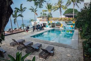 uma piscina num resort com palmeiras e o oceano em Solitude Acacia Resort em Mabini
