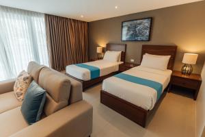 Habitación de hotel con 2 camas y sofá en Solitude Acacia Resort en Mabini