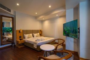 a bedroom with a bed and a table and a tv at Emerald Hotel in Āīzawl
