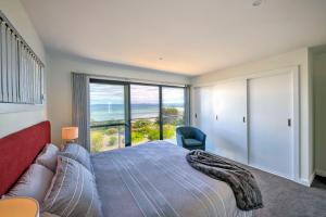 a bedroom with a bed and a large window at Tranquility in Coles Bay