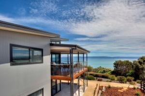 a house with a balcony with a view of the ocean at Tranquility in Coles Bay