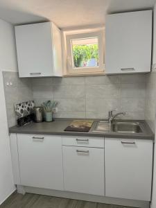 cocina con armarios blancos, fregadero y ventana en MARILU en Korčula