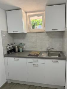 a kitchen with white cabinets and a sink and a window at MARILU in Korčula