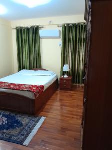 ein Schlafzimmer mit einem Bett und einem Tisch mit einer Lampe in der Unterkunft Apartment Rupas in Kathmandu