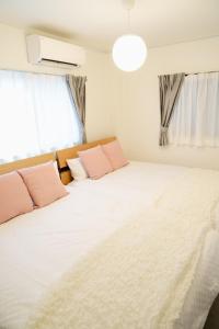 a bedroom with a large white bed with pink pillows at Liaison Court Universal Gateway in Osaka