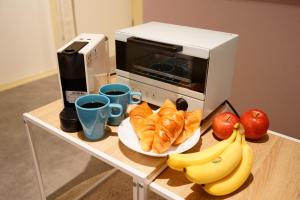 a table with a plate of croissants and apples and a microwave at Liaison Court Universal Gateway in Osaka