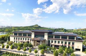 an aerial view of a building with a hill in the background at YunRay Hotel Shijiazhuang in Shijiazhuang
