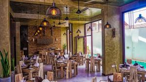 un restaurant avec des tables et des chaises en bois et un mur en briques dans l'établissement Hotel Sico, à Negombo