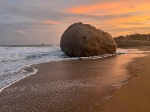 a large rock sitting on the beach near the ocean at Treasure Rock in Kirinda