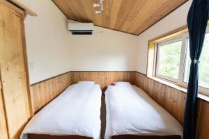 two beds in a small room with a window at Niseko Nikuyadoya in Niseko