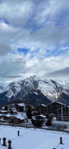 a snow covered mountain range with a city and buildings at Clair Vue A3 near Télécabine by Jolidi in Nendaz