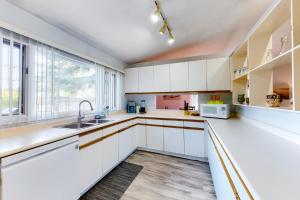 a kitchen with white cabinets and a window at The Gardenhouse Cottage One in Wasaga Beach