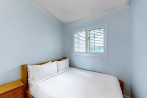 a white bedroom with a bed and a window at The Gardenhouse Cottage One in Wasaga Beach +21 photos