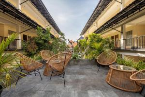 an outdoor patio with wicker chairs and plants at Cove Kanaya in Seminyak