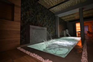 a bath tub with a waterfall in a room at Royal Wellness and Spa in Ruma