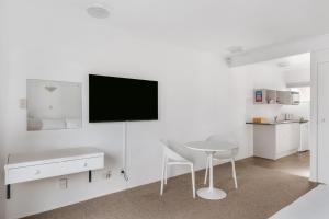 uma sala de estar branca com uma mesa e uma televisão na parede em Avalon Motel Thames - Wenzel Motels em Thames