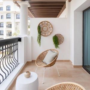 a balcony with a rattan chair and a table at Casa Noera, Yas Island 324 in Abu Dhabi