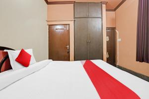 1 dormitorio con 1 cama blanca grande con detalles en rojo en Vj Hotel, en Rewāri