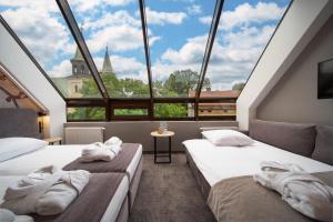 two beds in a room with a large window at Hotel Alexander in Krakow