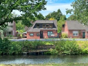 a house with a bridge over a river at Ferienwohnung No 1am Golfplatz in Wiesmoor
