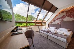 a bedroom with a bed and a desk and large windows at Hotel Alexander in Krakow