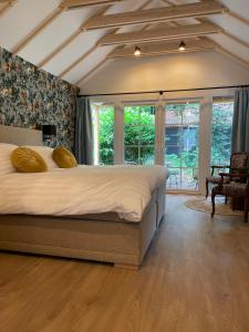 a bedroom with a large bed in a room with windows at Landgoedhotel Villa Vennendal in Nunspeet