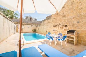 a patio with a table and chairs and a swimming pool at Ta' Gianni in Xewkija